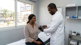 Médecin prenant la tension d'une patiente lors d'un bilan de santé en clinique à Abidjan