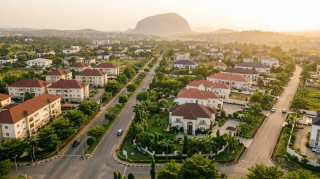 Aerial view of an upscale Abuja residential district with modern mansions, tree-lined boulevards and Aso Rock on the horizon